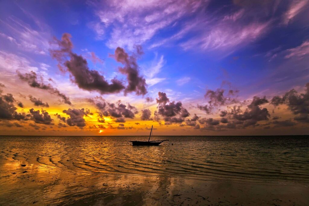 Boot auf Indischem Ozean bei Sonnenuntergang, Wolken am lila Himmel, Diani Beach